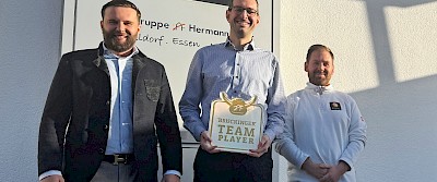 Vor der Niederlassung in Essen: Maximilian Hermann Brück (links) und Emanuel Hoff (rechts) überraschten Claus Ufermann mit der Auszeichnung zum Brückinger Teamplayer.