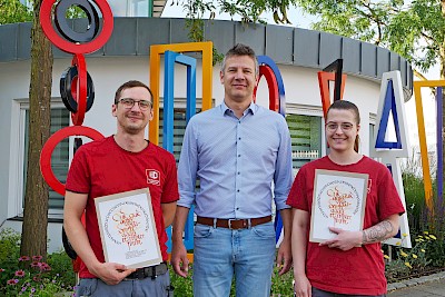 Mit frisch gedruckten Gesellenbriefen: Marius Greim und Jennifer Ottemeyer mit Ausbildungs-Verantwortlichem Christian Spiller